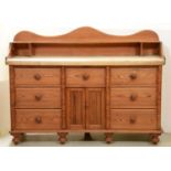 A Victorian pine dresser, with undulating upstand and scrubbed pine top, the front applied with