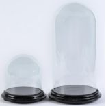 A glass dome, on black painted turned wooden circular base, 39cm h and another, 18cm h (2) Glasses