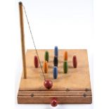 A table top skittle game, mid 20th c,  nine coloured skittles with detachable post and chained ball,