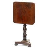 A Victorian mahogany lamp table, the oblong tip-up top on baluster pillar, platform and bun feet,