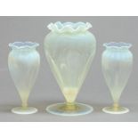 An Arts and Crafts semi-opalescent glass garniture of three vases, c1900, of flared shape and