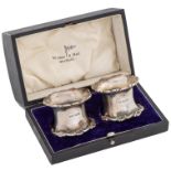 A pair of George V silver napkin rings, spool shaped, with applied border, by Walker & Hall Ltd,