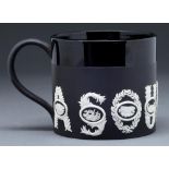 A Wedgwood black basalt sporting mug, designed by Richard Guyatt CBE, 1966, ornamented in white