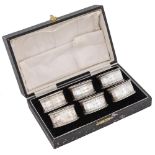 A set of six George V oval silver napkin rings, with engraved borders and beaded rims, by John Rose,