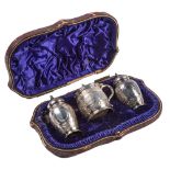 A Victorian three piece silver condiment set, chased with bands of foliage, mustard pot 63mm h,