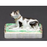 A Rockingham model of a recumbent dog, c1826-42, sponged in black on green base with fluted edge,