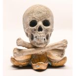 A macabre painted and giltwood memento mori in the form of a human skull and bones, on flared