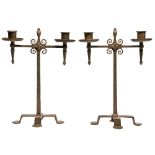 A pair of  Arts and Crafts wrought iron candelabra, of two torch-form lights, on tapered square