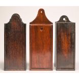 Three George III wall hanging candle boxes, one of mahogany, the others of oak, the back pierced for