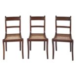 A set of three George IV mahogany dining chairs, on sabre legs, caned seat, seat height 44cm One