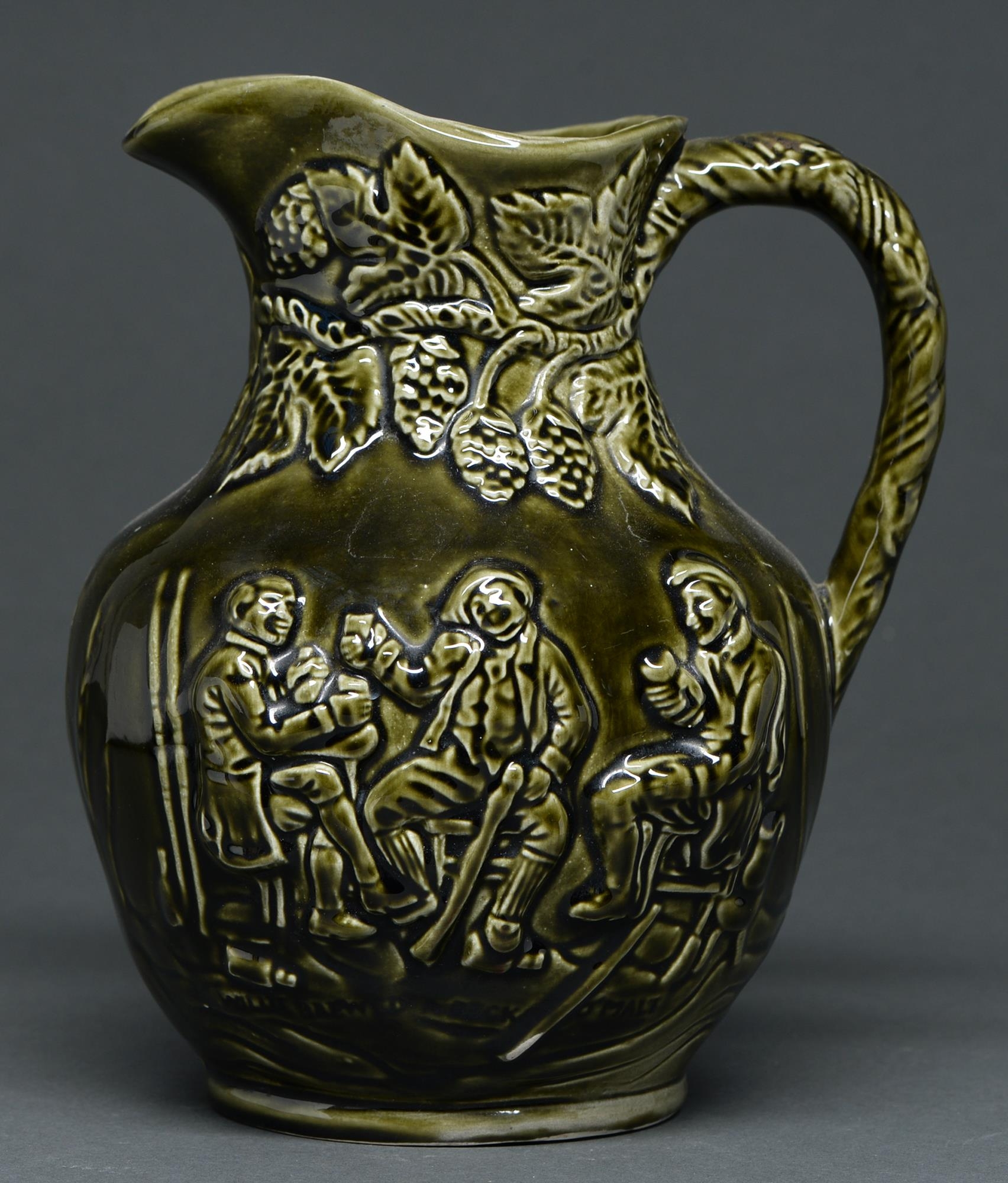 A Staffordshire olive green glazed moulded earthenware jug, late 19th c, with tavern scene, 22.5cm h