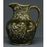 A Staffordshire olive green glazed moulded earthenware jug, late 19th c, with tavern scene, 22.5cm h