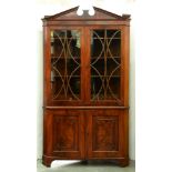 A George III mahogany standing corner cabinet, with open triangular pediment, the upper doors with