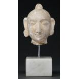 A plaster sculpture of the head of a deity, on marble base, 21cm h Some damage and repair