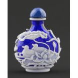 A Chinese cameo glass snuff bottle, 20th c,  in deep blue glass overlaid in white and carved with
