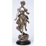 A silvered spelter statuette of a semi-naked maiden poised on the head of a dolphin, cast from a