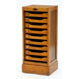 An oak office filing cabinet, c1930, fitted nine trays enclosed by a tambour shutter, 100cm h; 38