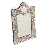 A George V silver dressing mirror, with die stamped rococo mount, re-backed on velvet, 34cm h, by