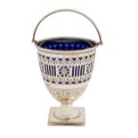 An Edwardian pierced and engraved silver sugar basket, with swing handle, on square foot, blue glass