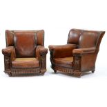 A pair of carved oak and close nailed brown hide easy armchairs, c1930, with Tudor style terms, seat