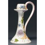 A Gouda art pottery hand candlestick, early 20th c, painted with stylised flowers on a cream ground,