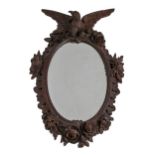 A German carved and stained wood oval mirror, late 19th c,  crested by an eagle in a rococo surround