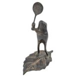 An anthropomorphic patinated brass sculpture of a frog holding a tennis racquet, 20th c, on leaf