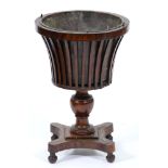 A Dutch mahogany teestof, 19th c,  the flared, slatted bowl with brass liner, on knopped pillar