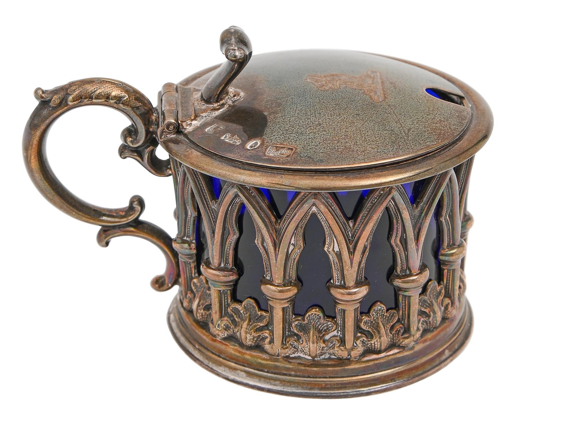 A Victorian gothic silver mustard pot, the sides pierced with arches and water leaves, crested, blue