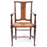 An Arts and Crafts walnut elbow chair, early 20th c, rush seated, on turned legs united by
