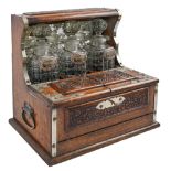 An Edwardian EPNS mounted and carved oak tantalus, with mirror back and twin lidded compartment