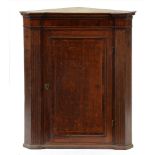 A George III oak, crossbanded and line inlaid hanging corner cupboard, with panelled door and fluted
