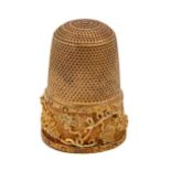 A gold thimble, c1900, with skirt of finely applied and chased grapevines, 24mm h, inscribed 15ct,