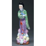 A Chinese famille rose figure of an immortal, 20th c,  in green and lavender robe standing on