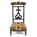 A French carved and turned ebonised wood prie dieu, late 19th c, upholstered in woolwork and velvet,