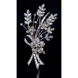 A diamond spray brooch, circa mid 20th c, the stems tied by a ribbon and set with round and baguette