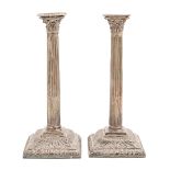 A pair of George III silver candlesticks, with gadrooned nozzle and square base, Corinthian