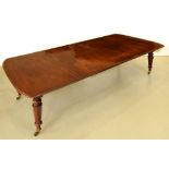 A Victorian mahogany dining table, on tapered octagonal legs and brass castors, with two leaves,