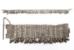 A late 19th century Omani white metal chain link bracelet with hanging bell decoration, 23cm long,