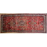 A Hamadan floral red-ground rug, woven with radiating floral medallions in cream, black,
