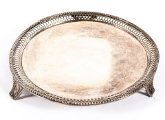 A sterling silver circular card tray with pierced border raised on three feet,