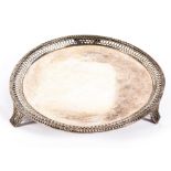 A sterling silver circular card tray with pierced border raised on three feet,