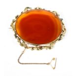 A late 19th century unmarked yellow metal brooch with oval set orange agate of oval form,