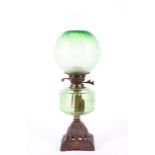 An Edwardian green glass oil lamp, the fluted shade etched with flowerheads and leafy branches,