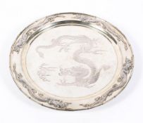 An early 20th century Chinese silver plated circular charger, on three bun feet,