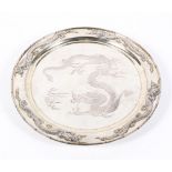 An early 20th century Chinese silver plated circular charger, on three bun feet,