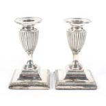 A pair of Edwardian squat silver candlesticks of urn form,