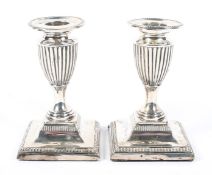 A pair of Edwardian squat silver candlesticks of urn form,