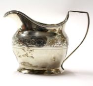 A George III silver cream jug, adorned with chased and engraved foliate band decoration,