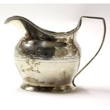 A George III silver cream jug, adorned with chased and engraved foliate band decoration,